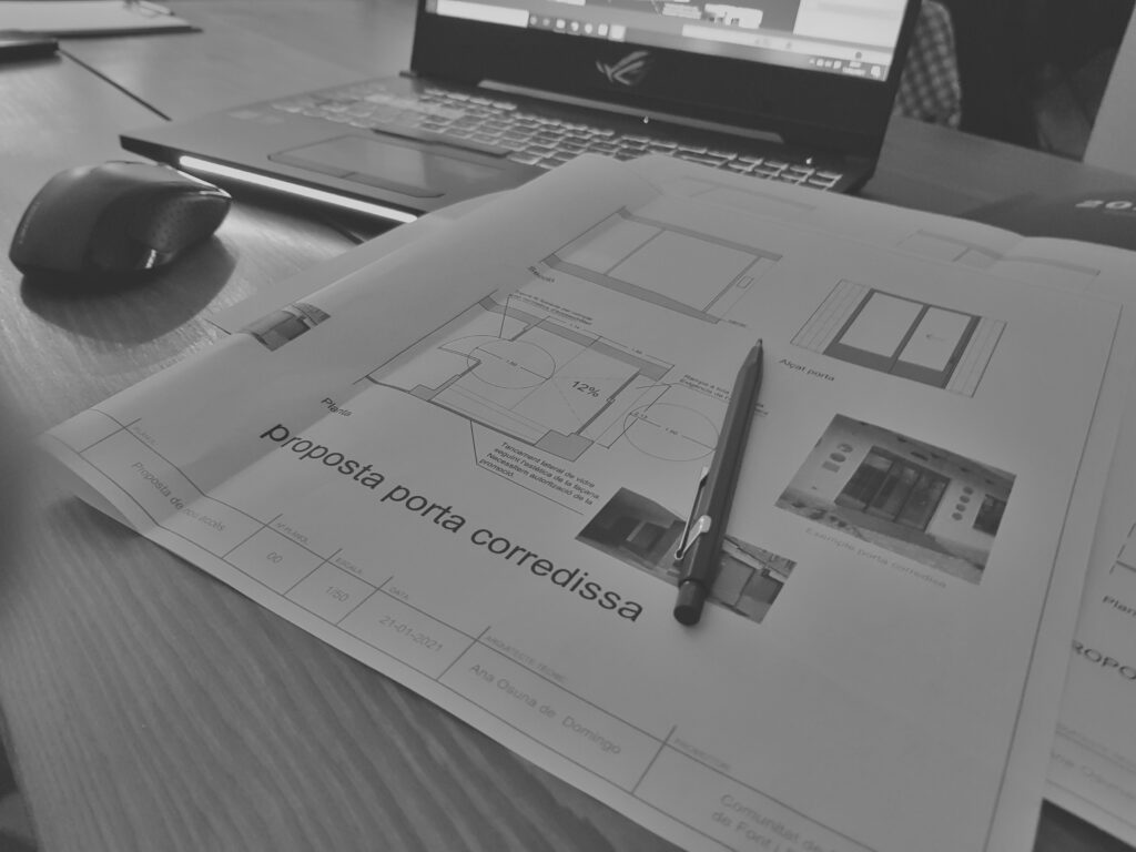 Plano de vivienda sobre mesa con boli encima
