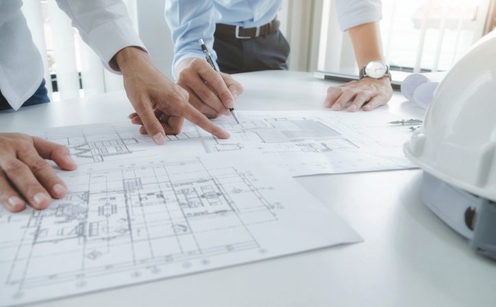 Arquitectos elaborando planos de construcción de vivienda de obra nueva